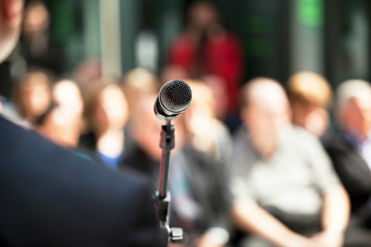 man standing on a stage speaking into a microphone