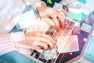 image of cyber items floating above a woman working on a laptop