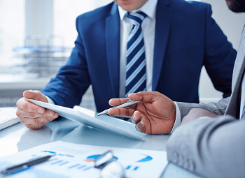 Two people dressed in business suits going over papers together